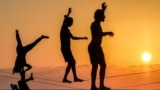 People walk on a tightrope along the Mediterranean sea waterfront in Tel Aviv at sunset, Oct. 10, 2024. 