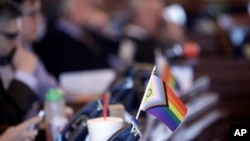 Bendera kecil yang melambangkan hak-hak kelompok LGBT tertata di sebuah meja di sisi anggota Partai Demokrat di DPR Kansas di Topeka, pada 28 Maret 2023. (Foto: AP/John Hanna)