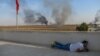 A journalist takes cover in Akcakale near the Turkish border with Syria, Oct. 10, 2019, as a mortar lands nearby on the second day of Turkey's military operation against Kurdish forces.