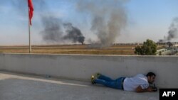 A journalist takes cover in Akcakale near the Turkish border with Syria, Oct. 10, 2019, as a mortar lands nearby on the second day of Turkey's military operation against Kurdish forces.