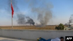 A journalist takes cover in Akcakale near the Turkish border with Syria, Oct. 10, 2019, as a mortar lands nearby on the second day of Turkey's military operation against Kurdish forces.