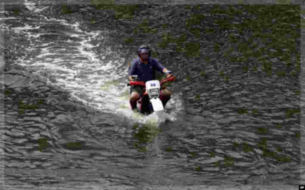 A man rides his motorcycle along a flooded street in Bangkok November 5, 2011. As waterlogged Thailand struggles to contain the worst floods in decades, it faces a simple truth: not a whole lot can be done to avoid a repeat disaster in the short term even