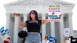 Terrisa Bukovinac, founder of Pro-Life San Francisco, holds a model of a fetus as she and other anti-abortion protesters wait outside the Supreme Court for a decision, June 29, 2020. 