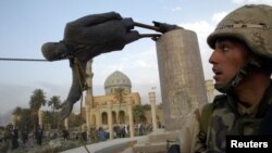 A U.S. soldier watches as a statue of Iraq's President Saddam Hussein falls in central Baghdad in this photo dated April 9, 2003.