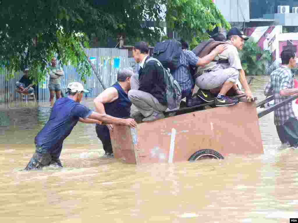 Masyarakat mengungsi dari banjir dengan menggunakan gerobak (13/1). (VOA/Iris Gera)