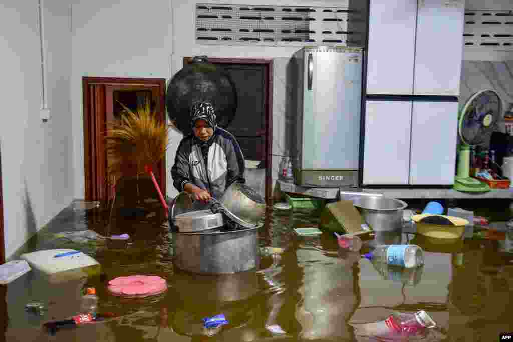 A resident looks pots floating in flood waters inside her kitchen following heavy rain in Thailand&#39;s southern province of Narathiwat.