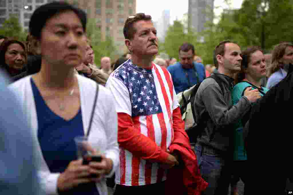 A somber crowd watches President Obama giving a speech on a projection screen during the dedication ceremony of the National September 11 Memorial Museum, in New York City, May 15, 2014.