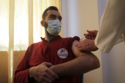FILE - A man receives a dose of the coronavirus vaccine at a hospital in Idlib, Syria, May 1, 2021.