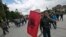 FILE - An ethnic Albanian holding an Albanian flag walks in the capital, Pristina, to protest the prison sentences for former rebels for war crimes committed during the 1998-99 war. The Specialist Chamber, a court set up in The Hague in 2015, has been working for years to handle cases of alleged crimes by the Kosovo Liberation Army (KLA) guerrillas. That court has yet to hear any cases.