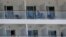 In this May 8, 2020 photo, people aboard the Norwegian Epic cruise ship docked at PortMiami in Miami, sit on their balconies. Tens of thousands of crew members, including U.S. citizens, remain confined to cabins aboard cruise ship.