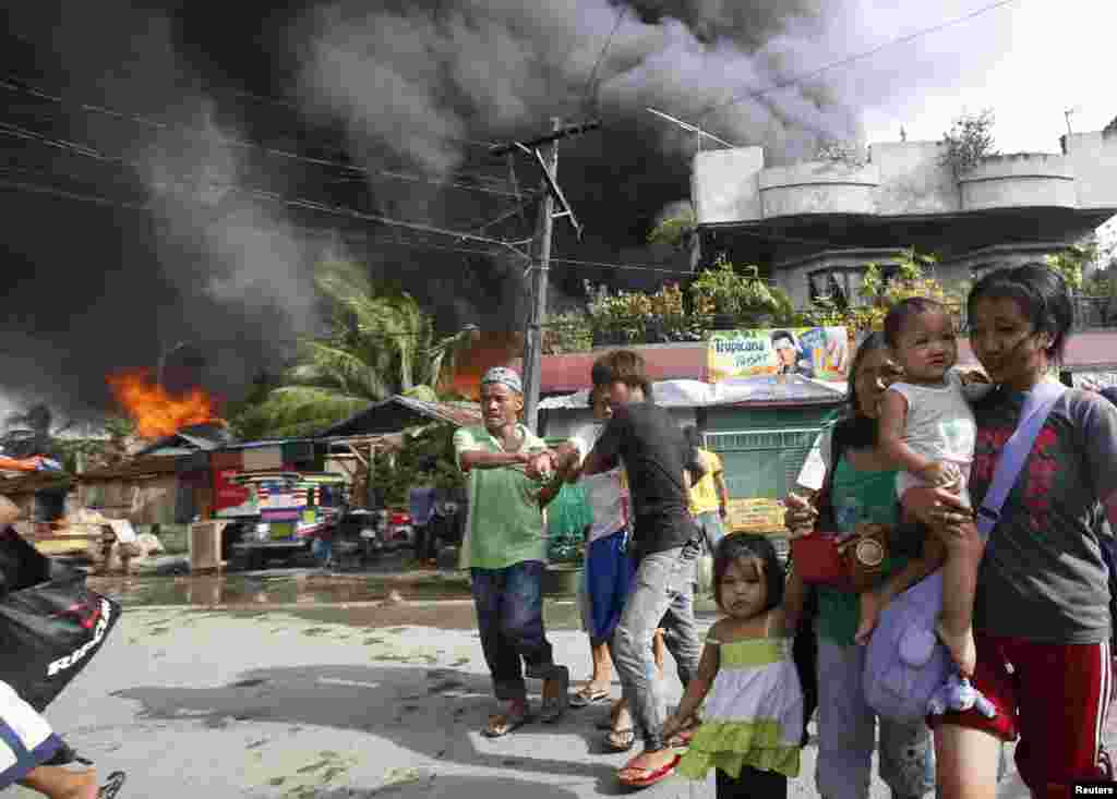 Residents evacuate as houses burn in a residential district after a clash between government soldiers and Muslim rebels in Zamboanga, Philippines, Sept. 12, 2013.