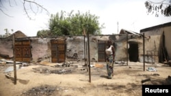 Une femme débour devant des maisons incendiées lors d'une attaque de Boko Haram au village de Michika, dans l'Etat d' Adamawa dimanache 10 mai 2015.