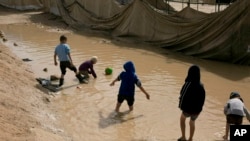 FILE - children play in a mud puddle in the section for foreign families at Al-Hol camp in Hasakeh province, Syria.