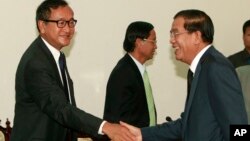 Cambodian Prime Minister Hun Sen, right, shakes hands with opposition leader Sam Rainsy before a meeting at the National Assembly in Phnom Penh, Cambodia, Sept. 17, 2013.