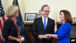 New York Chief Judge Janet DiFiore, left, swears in Kathy Hochul, right, as the first woman to be New York's governor while her husband Bill Hochul holds a bible during a swearing-in ceremony in the Red Room at the state Capitol, early Tuesday, Aug…