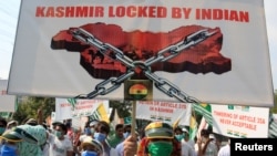 People carry signs as they mark one year after the Indian government split the state of Jammu and Kashmir into two federally controlled territories and took away its special privileges, during a march in Lahore, Pakistan, Aug. 5, 2020.