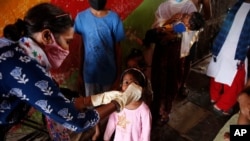 Seorang petugas kesehatan memberikan imunisasi polio kepada seorang anak di kawasan kumuh di Mumbai, India, 27 Juni 2021. (Foto: AP Photo/Rafiq Maqbool)