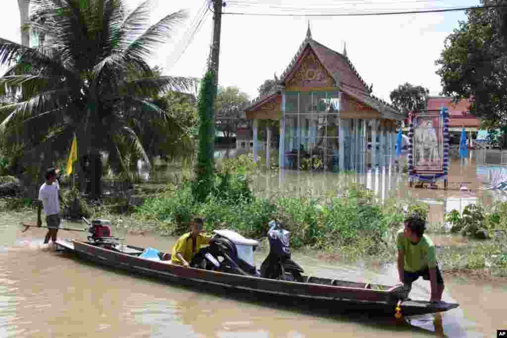 Men transport a motorcycle in a boat past the flooded Buddhist temple in Ayutthaya, October 6, 2011. (VOA - D. Schearf)