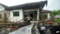 A police officer inspects the damage at the house of a member of Ahmadiyah sect after it was attacked by Muslim mob in Pandeglang, Banten province, Indonesia, February 7, 2011.