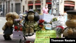 Flores y carteles rodean la escultura de los personajes de la tira cómica Mafalda, en Buenos Aires, tras la muerte de su creador, Quino. Octubre 1 de 2020.