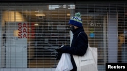 FILE - A shopper passes by a retail store that was recently closed in Brooklyn, New York, Dec. 8, 2020. 