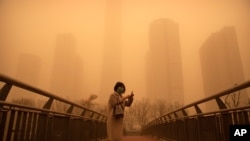 A woman walks along a pedestrian bridge amid a sandstorm during the morning rush hour in the central business district in Beijing, March 15, 2021. 