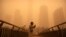 A woman walks along a pedestrian bridge amid a sandstorm during the morning rush hour in the central business district in Beijing, Monday, March 15, 2021. The sandstorm brought a tinted haze to Beijing's skies and sent air quality indices soaring on…