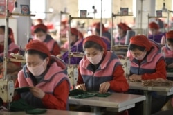 FILE - Workers produce masks for protection against the new coronavirus, at the Songyo Knitwear Factory in Pyongyang, Feb. 6, 2020.