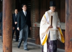 FILE - Japanese Prime Minister Shinzo Abe, center, follows a Shinto priest to pay respect to the war dead at Yasukuni Shrine in Tokyo, Japan, Dec. 26, 2013.