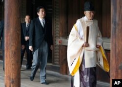 FILE - Japanese Prime Minister Shinzo Abe, center, follows a Shinto priest to pay respect to the war dead at Yasukuni Shrine in Tokyo, Japan, Dec. 26, 2013.