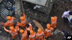 FILE - Rescuers with the help of a sniffer dog look for survivors after a residential building collapsed in Bhiwandi in Thane district, a suburb of Mumbai, Sept.21, 2020. 