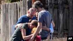 Un grupo ora con un niño afuera del centro de reunificación en la iglesia bautista de Woodmont después de un tiroteo en una escuela, el lunes 27 de marzo de 2023, en Nashville, Tennessee.