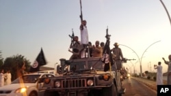 FILE - Islamic State militants flaunt an armored vehicle seized from Iraqi security forces in the northern Iraq city of Mosul on June 23, 2014.