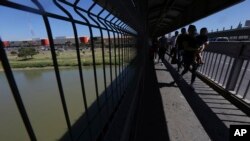FILE - People walk back to Mexico on International Bridge 1 Las Americas, a legal port of entry which connects Laredo, Texas, in the U.S. with Nuevo Laredo, Mexico, July 18, 2019.
