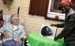 Eric Baranyanka, right, and his foster mother Emma Monsaert look at a photo of Eric as a young boy in Lembeek, Belgium, June 22, 2020.