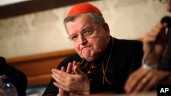 FILE - Cardinal Raymond Burke applauds at the Italian Senate, in Rome, on Sept. 6, 2018. Pope Francis has taken measures to punish Burke, one of his highest-ranking critics, by yanking his right to a Vatican apartment and salary. 