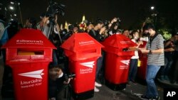 Seorang demonstran pro-demokrasi memasukkan surat yang berisi tuntutan di kotak pos-kotak pos buatan untuk Raja Thailand, dalam demonstrasi di Bangkok, Thailand, Minggu, 8 November 2020. (Foto: AP)