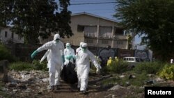 A burial team wearing protective clothing remove the body of a person believed to have died of Ebola in Freetown, Liberia, Sept. 28, 2014. 