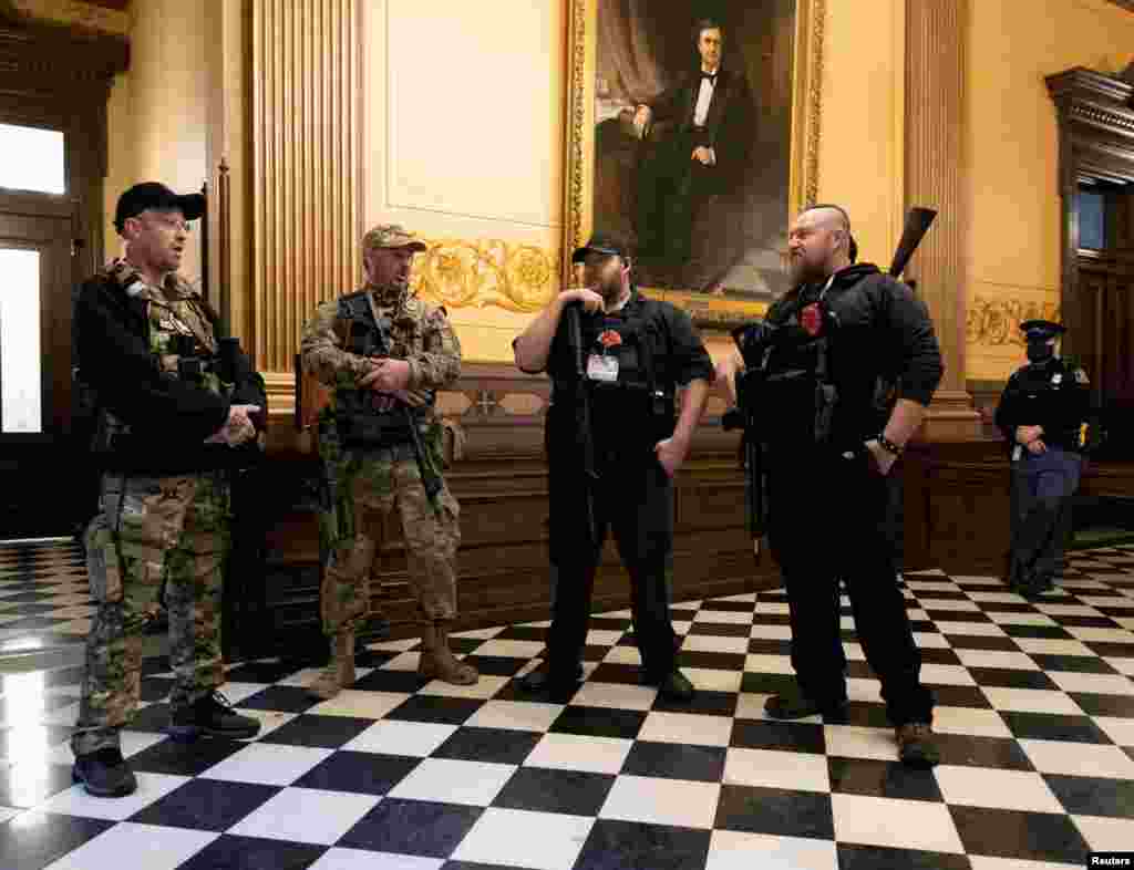 Members of a militia group stand near the doors to the chamber in the capitol building before the vote on the extension of Governor Gretchen Whitmer&#39;s emergency declaration/stay-at-home order due to the COVID-19 outbreak, in Lansing, Michigan.