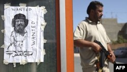 Pripadnik pobunjeničkih snaga pored crteža Moamera Gadafija na kontrolnom punktu u Tripoliju, 30. avgust 2011.