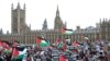 Protesters hold placards and wave Palestinian flags as they walk over Westminster Bridge with the Palace of Westminster, home of the Houses of Parliament, behind them in London on Oct. 28, 2023.