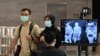 Sepasang suami istri, mengenakan masker di tengah kekhawatiran tentang penyebaran virus corona baru COVID-19, berjalan melewati pemeriksaan pemeriksaan suhu di Bandara Internasional Changi di Singapura, 27 Februari 2020. (Foto: AFP)