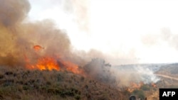 Pekerja Israel dari Nature and Parks Authority mencoba memadamkan api yang disebabkan oleh balon api yang diluncurkan dari Jalur Gaza, dekat Be'eri Kibbutz, 13 Agustus 2020. (Foto: AFP/Jack Guez)