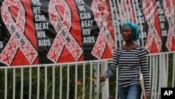 In this Friday, Dec. 1, 2017 file photo, a woman walks past a World AIDS Day banner in Johannesburg, South Africa.