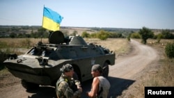 Ukrainian servicemen speak near an armored vehicle in their camp near Donetsk Sept. 2, 2014. 