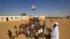 FILE - Displaced Sudanese children gather under the national flag in a school yard, Feb. 1, 2021. Six children died after a metal device exploded near a refugee settlement in northwestern Uganda.