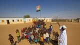 FILE - Displaced Sudanese children gather under the national flag in a school yard, Feb. 1, 2021. Six children died after a metal device exploded near a refugee settlement in northwestern Uganda.