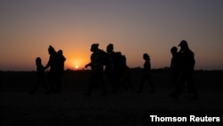 El sol sale mientras las familias de migrantes en busca de asilo de Honduras y El Salvador caminan hacia el muro fronterizo después de cruzar el río Grande hacia Estados Unidos, el 26 de marzo 2021.