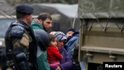 Macedonian soldiers escort migrants who have crossed the border illegally from Greece, into army trucks in the village of Moini, Macedonia, March 14, 2016. About 600 refugees who managed to cross over have been returned to greecce.