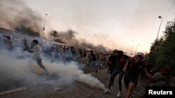 Sejumlah demonstran tampak berlarian saat petugas keamanan Irak berusaha membubarkan massa dengan menembakkan gas air mata dalam aksi protes antipemerintah di Baghdad, Irak, pada 5 Oktober 2019. (Foto: Reuters/Thaier Al-Sudani) 